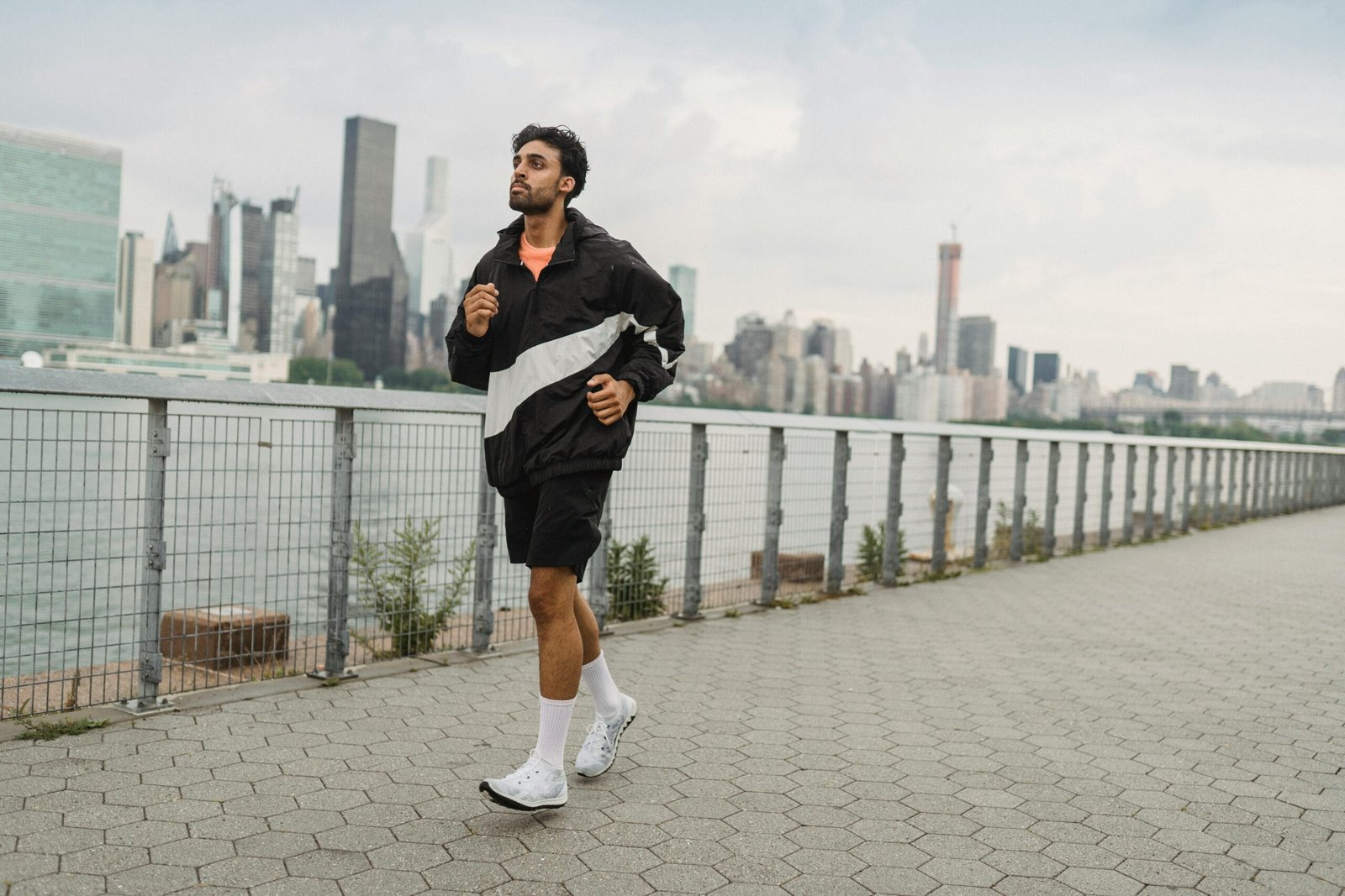 A man jogs along a riverside path with a city skyline in the background, promoting healthy living.